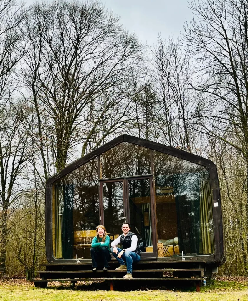 Aukje van de Gerven and Simon Collier sitting in front of cabin, where nature positive tourism training takes place.